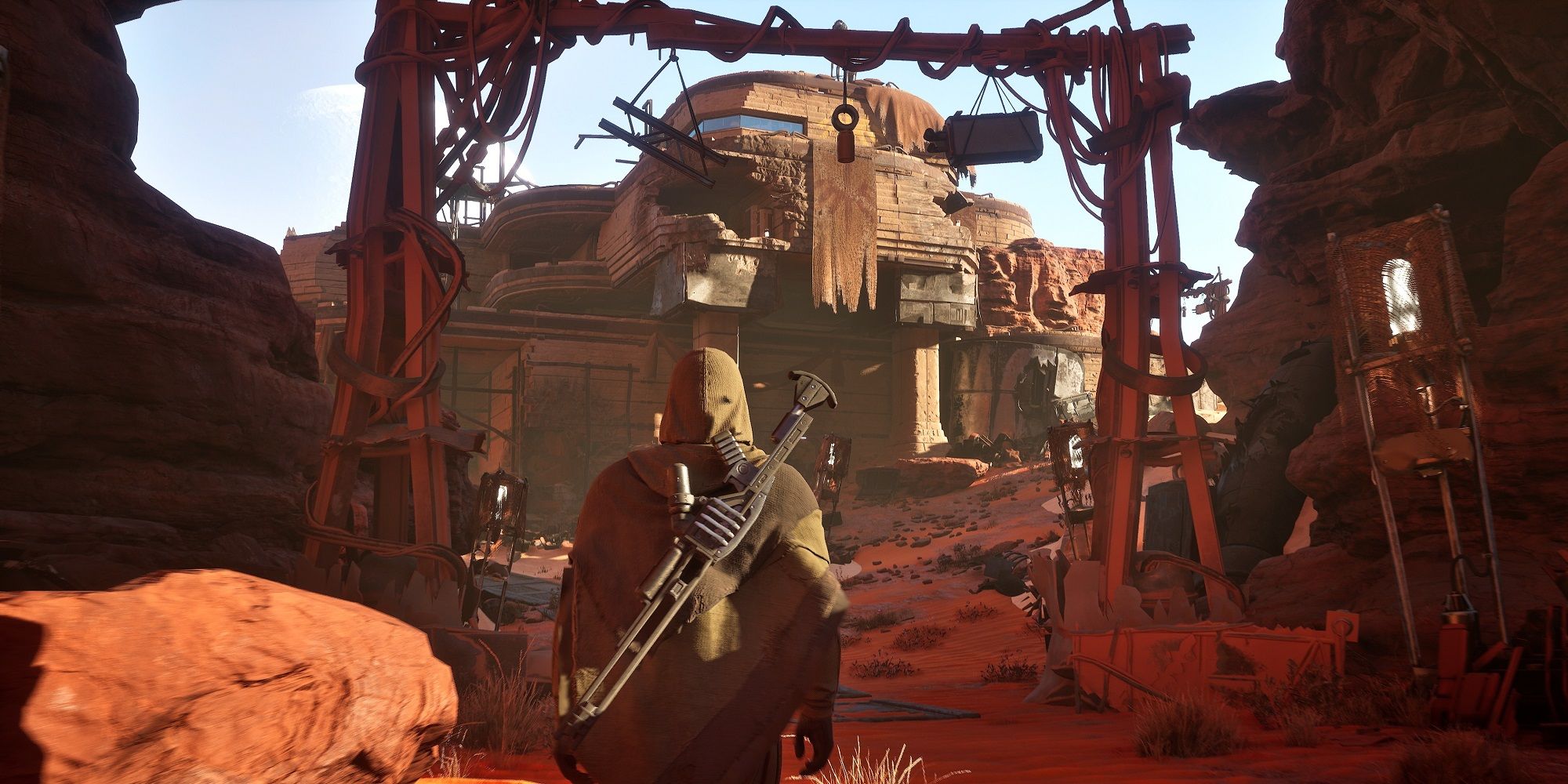 Dune Awakening character looks at a settlement built in the desert full of scrapped together parts and a central building