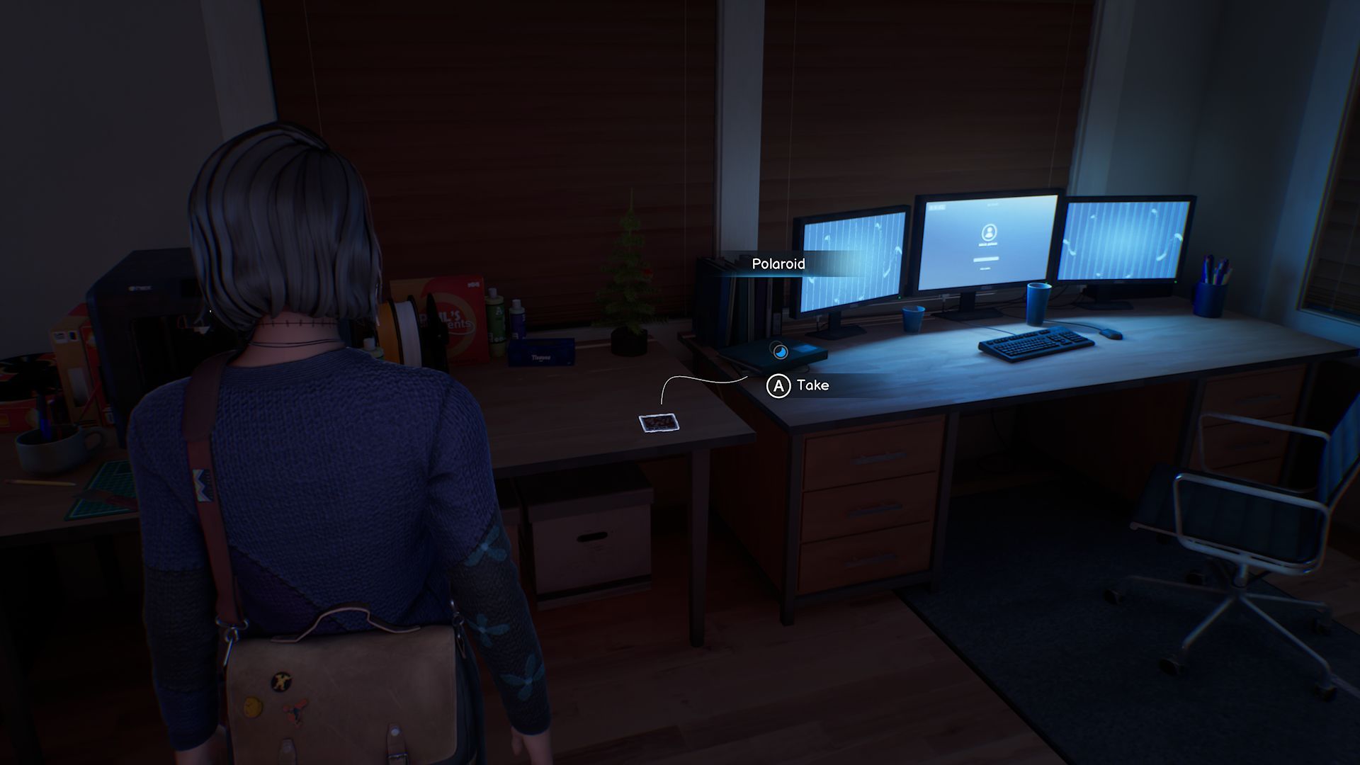 A screenshot with Max standing in front of the fourth Polaroid in Chapter 2, located on a desk next to three computer monitors, all glowing blue.