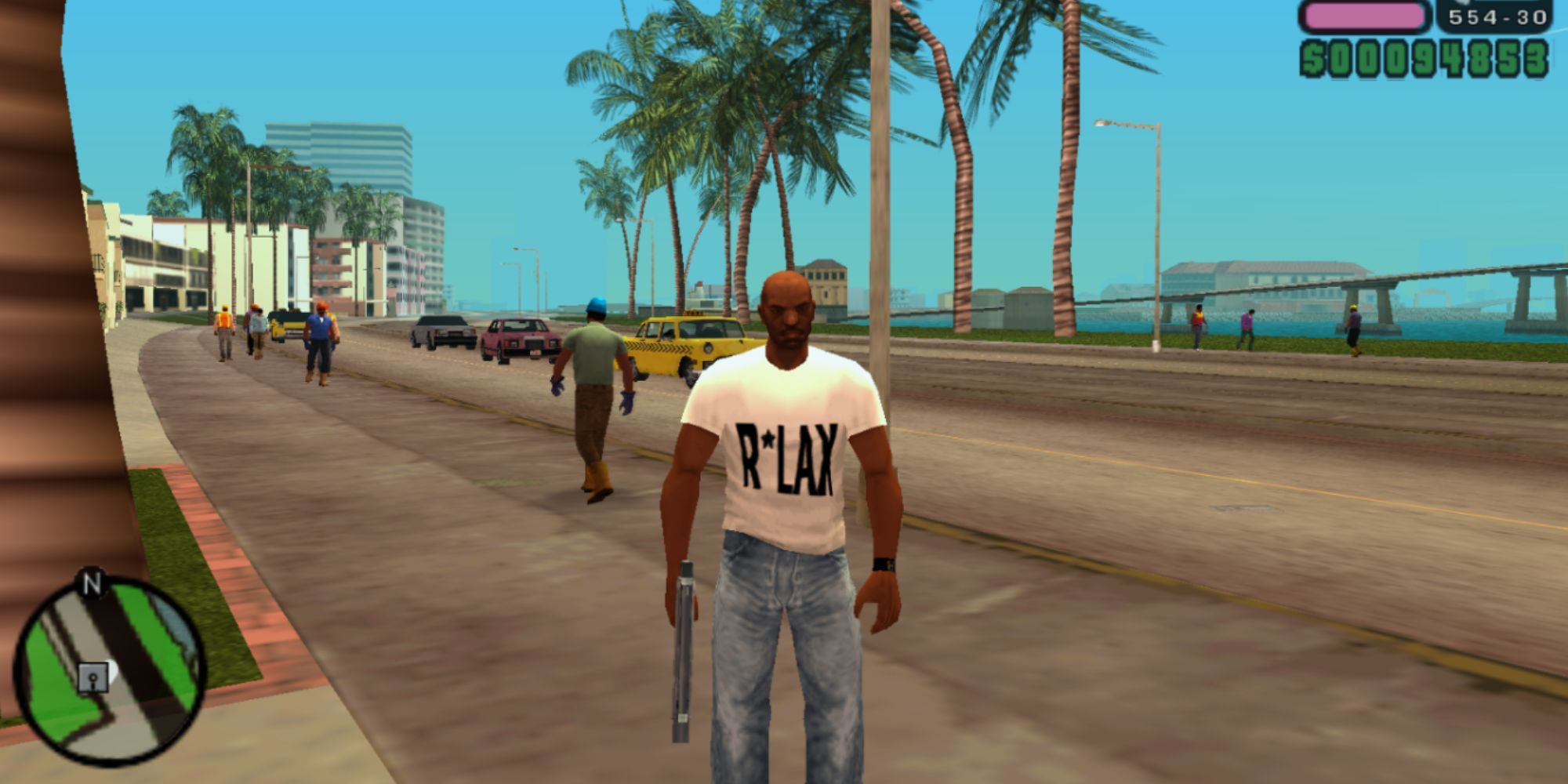 Victor Vance standing on beachside road with a gun in hand in GTA Vice City Stories